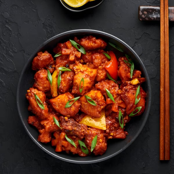 Masthi Indian Cuisine's chili chicken, a vibrant dish with red and yellow peppers, and green onions.